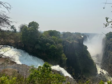 Majestätische Wasserfälle stürzen über steile Klippen, umgeben von üppigem Grün und einem nebligen Wassernebel.