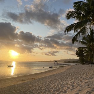 Ein malerischer Strand bei Sonnenuntergang, mit sanften Wellen und einer kleinen Boot auf dem Wasser.