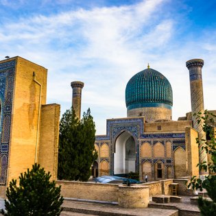 Die beeindruckende Architektur von Samarkand zeigt eine große Kuppel und kunstvoll verzierte Wände unter einem blauen Himmel.