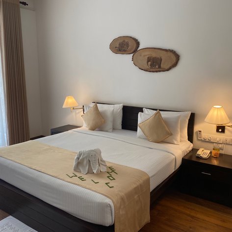 Ein elegantes Hotelzimmer mit einem großen Bett, dekoriert mit Kissen und einem handtuchförmigen Elefanten auf der Bettdecke.