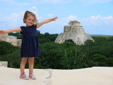 Kleines Mädchen lächelnd vor der Pyramide in Uxmal – Mexiko Familienreise