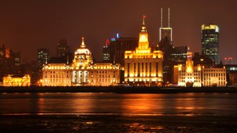 Der Waitan in Shanghai erstrahlt nachts in Beleuchtung mit Blick auf die Skyline – China Familienreise