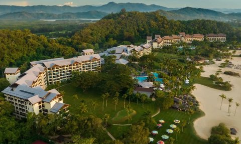 Ein luxuriöses Resort eingebettet in üppige Natur, mit mehreren langen Gebäuden und einem glitzernden Poolbereich.
