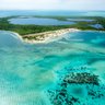 Eine atemberaubende Luftaufnahme einer tropischen Insel mit üppigem Grün und klarem, türkisfarbenem Wasser umgeben.