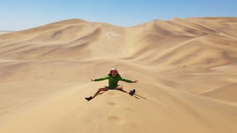 Ein Kind sitzt auf den Kamm einer Düne in der Wüste - Namibia Urlaub mit Kindern