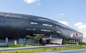 Ein modernes, schwarzes Gebäude mit großen Fenstern und dem Schriftzug 'Wyndham' an der Fassade, umgeben von Grünflächen.