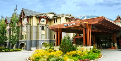 Das Aava Hotel in Whistler zeigt eine moderne Architektur mit Holzverkleidung und großen Fenstern, umgeben von bunten Blumen.