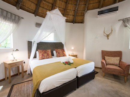 Ein gemütliches Zimmer mit einem Doppelbett, dekoriert mit bunten Kissen und einem frischen Blumenarrangement auf der Bettdecke.