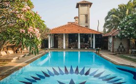 Ein einladender Pool mit blauen Fliesen und einem auffälligen Muster, umgeben von üppigem Grün und blühenden Bäumen.