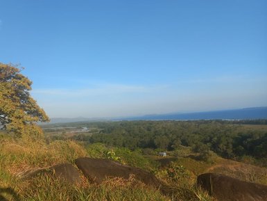 Eine Person reitet auf einem Pferd mit Blick auf eine weite Küstenlandschaft unter einem klaren, blauen Himmel.
