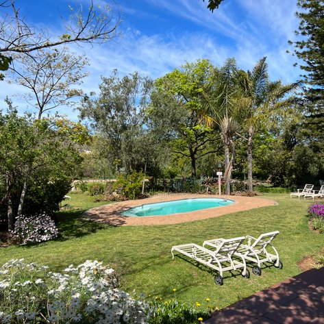 Ein einladender Pool umgeben von üppigem Grün und bunten Blumen, ideal für entspannende Tage im Freien.
