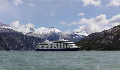 Ein großes Kreuzfahrtschiff gleitet durch die ruhigen Gewässer der Fjorde, umgeben von majestätischen, schneebedeckten Bergen.