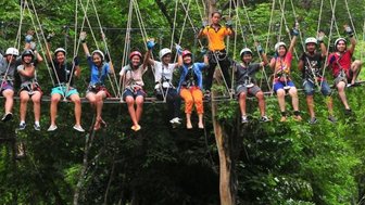 Teens sitzen auf einer Hängebrücke im Treetop Adventure Park in Kanchanaburi - Thailandreise mit Kindern