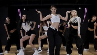 Eine Gruppe von Tänzerinnen in sportlicher Kleidung führt synchronisierte Bewegungen in einem modernen Tanzstudio aus.