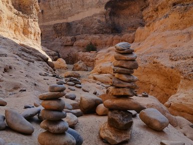 Mehrere Steine sind aufeinander gestapelt und bilden zwei Steintürme - Namibia mit Kindern