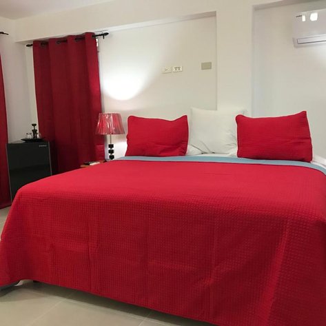 Ein gemütliches Schlafzimmer mit einem großen roten Bett und passenden Vorhängen, das eine einladende Atmosphäre schafft.