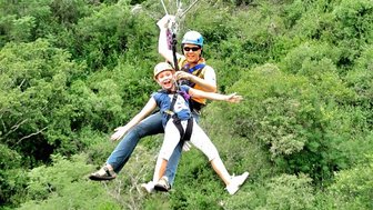 Fröhliches Kind beim Ziplining über Baumwipfel in einem Abenteuerpark in Südafrika – Südafrika Reise mit Kindern