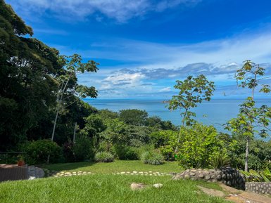 Ein atemberaubender Blick auf das Meer, umgeben von üppigem Grün und strahlend blauem Himmel, der Ruhe ausstrahlt.