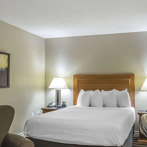 Ein gemütliches Hotelzimmer mit einem großen Bett, umgeben von sanften Farben und einer modernen Lampe auf dem Nachttisch.