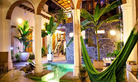 Ein einladender Innenhof mit einem kleinen Pool, umgeben von tropischen Pflanzen und einer gemütlichen Hängematte.