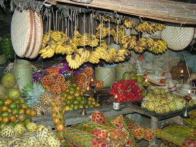 Ein lebhafter Marktstand mit einer Vielzahl tropischer Früchte, darunter Bananen, Ananas und exotische Früchte in bunten Verpackungen.