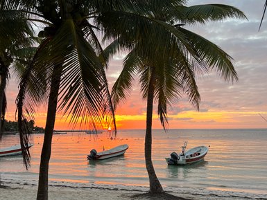 Bunte Abendstimmung am Strand von Akumal mit Palmen und Booten im Wasser – Mexiko Familienreise