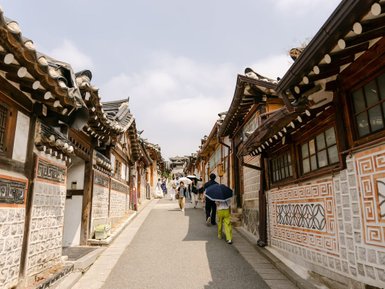 Eine belebte Straße im Bukchon Hanok Village, gesäumt von traditionellen koreanischen Häusern mit charakteristischen Dächern.