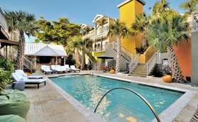 Ein einladender Poolbereich mit Liegen, umgeben von Palmen und bunten Gebäuden in Florida, ideal für Entspannung.