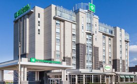 Das Wyndham Garden Hotel zeigt eine moderne Architektur mit großen Fenstern und einem klaren blauen Himmel im Hintergrund.