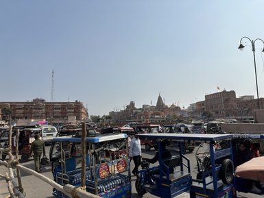 Ein belebter Platz in Jaipur, gefüllt mit zahlreichen Autorikschas und Menschen, die geschäftig umhergehen.