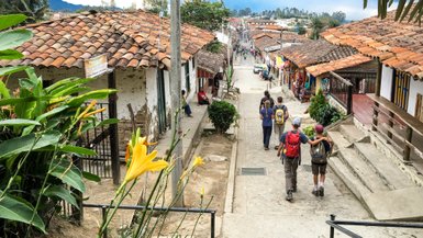 Eine belebte Straße in Salento, Kolumbien, mit bunten Häusern und Menschen, die die Atmosphäre genießen.