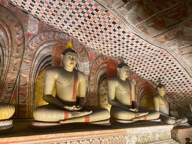 Mehrere nebeneinander sitzende Buddha-Statuen im Dambulla-Höhlentempel – Sri Lanka Familienreise