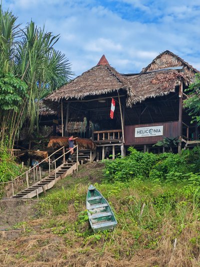 Ein traditionelles, strohgedecktes Gebäude in der Amazonasregion, umgeben von üppigem Grün und einem blauen Himmel.