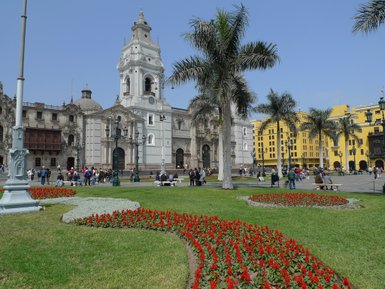 Der Hauptplatz in Lima zeigt eine lebendige Szenerie mit blühenden Blumenbeeten und historischen Gebäuden im Hintergrund.