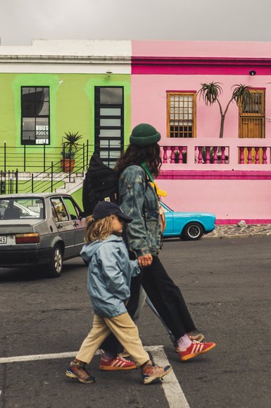 Mutter und Kind laufen durch die bunten Straßen im Bo-Kaap – Südafrika Familienreise