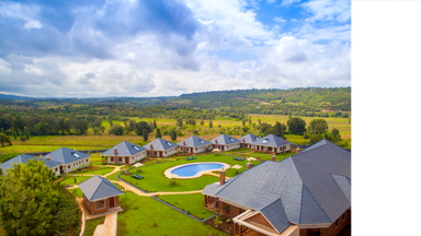 Eine weitläufige Landschaft mit modernen Villen und einem glitzernden Pool, umgeben von sanften Hügeln und bewölktem Himmel.