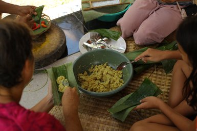Mehrere Einheimische bereiten zusammen balinesisches Essen zu – Bali Reise mit Kindern