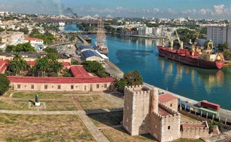 Ein Blick auf die Festung Ozama in Santo Domingo, umgeben von grünen Bäumen und dem glitzernden Wasser des Flusses.