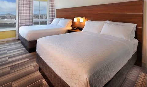 Das Hotelzimmer präsentiert zwei komfortable Doppelbetten mit weißer Bettwäsche und moderner Einrichtung.
