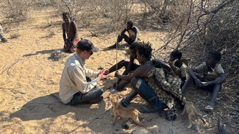 Besucher übt traditionelle Feuertechnik mit dem Hadzabe-Stamm – Tansania Reise mit Kindern