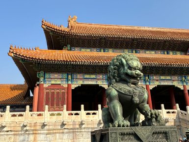 Ein majestätischer Löwenstatue bewacht den Eingang eines prächtigen, traditionell chinesischen Gebäudes mit kunstvollen Dächern.