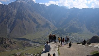 Eine Gruppe von Touristen steht auf einem Aussichtspunkt und bewundert die majestätischen Berge und das Tal darunter.