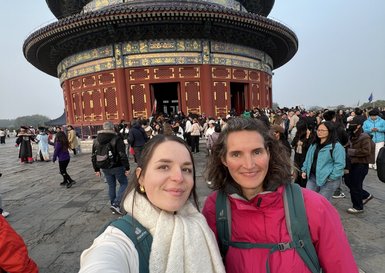 Zwei Frauen posieren lächelnd vor dem beeindruckenden Himmelstempel in Peking, umgeben von einer großen Menschenmenge.
