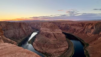 Der Sonnenuntergang über dem Horseshoe Bend zeigt die beeindruckenden roten Felsen und den geschwungenen Flussverlauf.