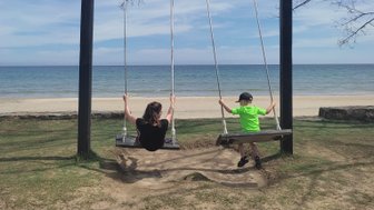Zwei Kinder schaukeln am Strand des Nexus Resorts – Malaysia & Borneo Familienreise