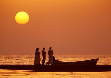 Omanis beobachten den Sonnenuntergang am Strand im Oman – Oman Reise mit Kindern