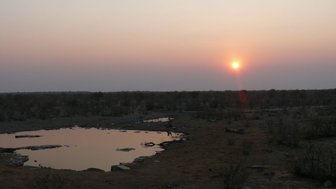 Die Sonne verschwindet hinter dem Horizont am Moringa Wasserloch - Namibia mit Kindern