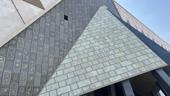 Moderne Architektur des Neuen Ägyptischen Museums mit einer markanten Pyramidenform und Hieroglyphen an der Wand.