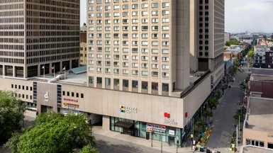 Ein modernes Hotelgebäude mit großen Fenstern und einem klaren, strukturierten Design in der Innenstadt von Montreal.