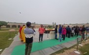 Eine Gruppe von Menschen steht in einem Park, einige machen Fotos, während andere in bunten Kleidern posieren.
